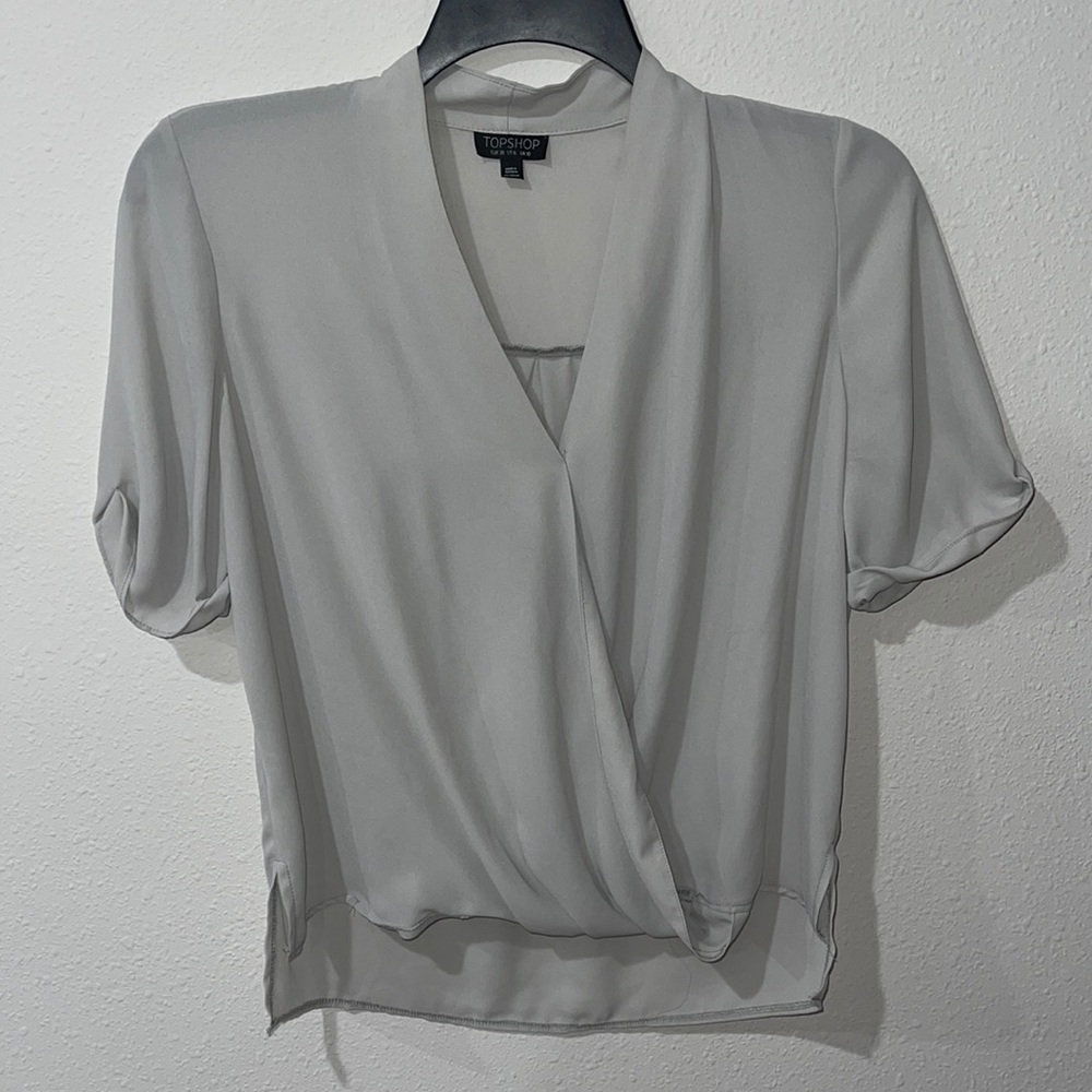 A light Gray loose fitting Topshop women’s short sleeved top. Size 6